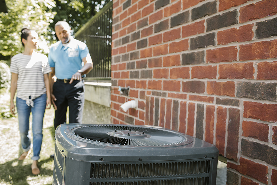 Homeowner and contractor walking together to air conditioner