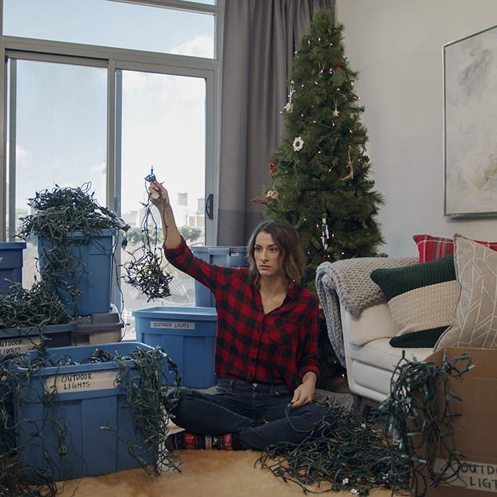 Woman struggling with tangled Christmas lights (at least they're LEDs).