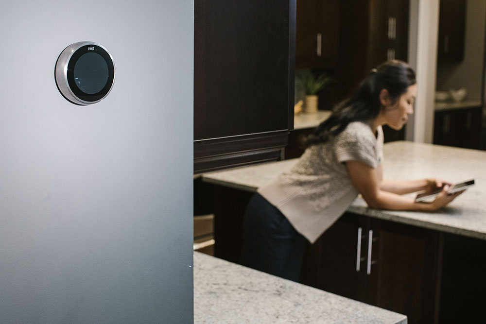 woman controlling her smart thermostat from her smart phone at home