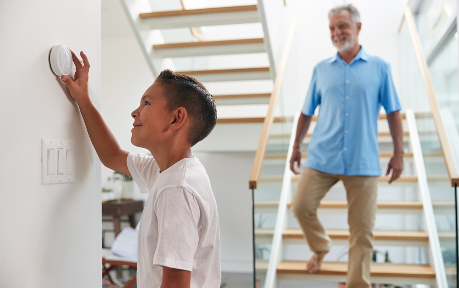 Father watching son set smart thermostat