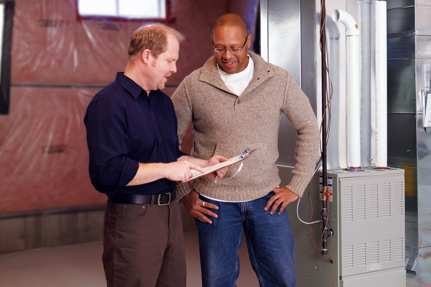 professional and resident having discussion in front of basement furnace