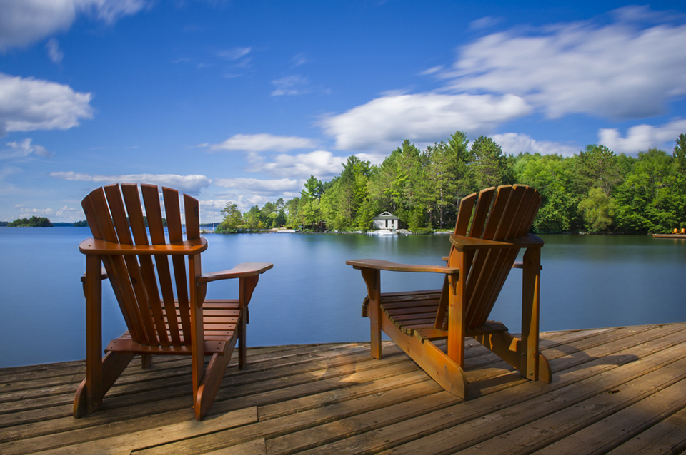 Two Muskoka chairs on a dock by the lake