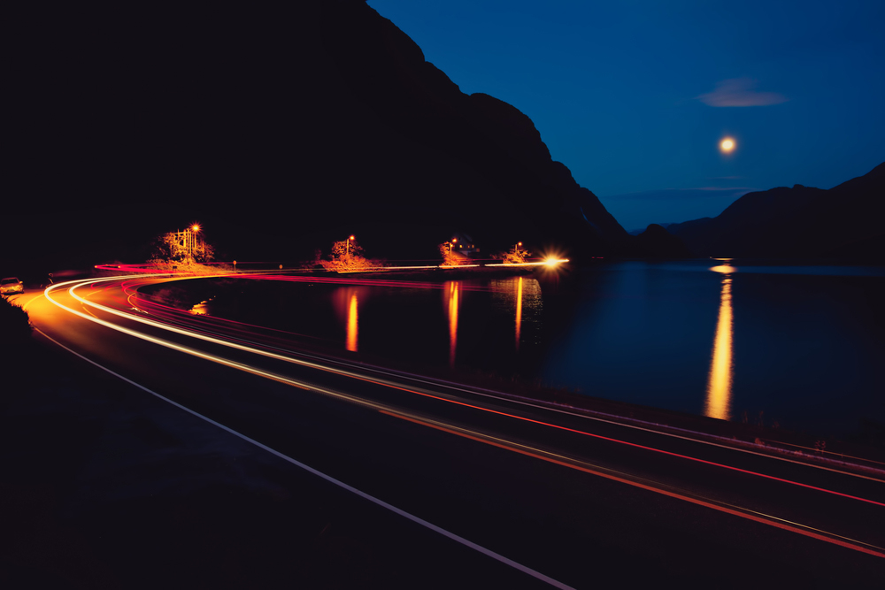 auto-dimming streetlights on road by the sea at night
